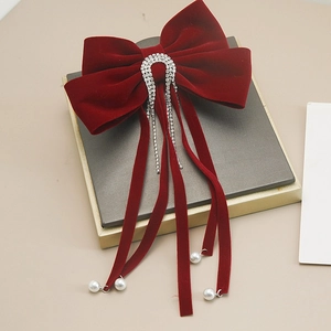 Dettaglio macro del fiocco in velluto rosso con strass e nappe di perle bianche