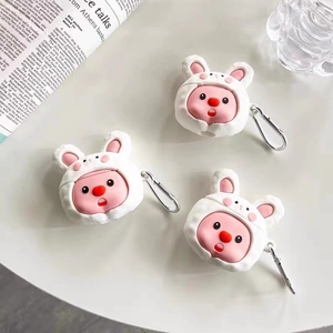 Close-up of cute rabbit silicone AirPods cases with silver carabiners on a desk