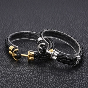 Close-up of double-layered black leather braided bracelets with gold and silver anchor clasps