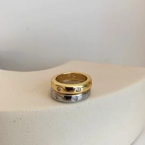 Primer plano de anillos de latón dorado y plateado con circonita en un soporte minimalista