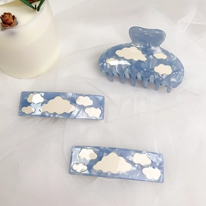 Blue marble acetate hair claw set with white cloud patterns on soft fabric background