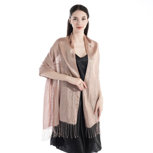 Close-up of golden shimmering fabric texture with elegant fringe detail on a shawl