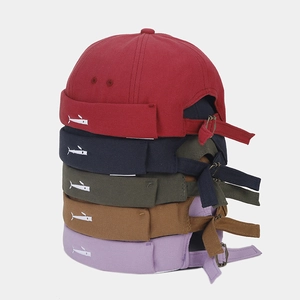 Detail of stacked brimless caps in five colors with side fish embroidery and metal buckle