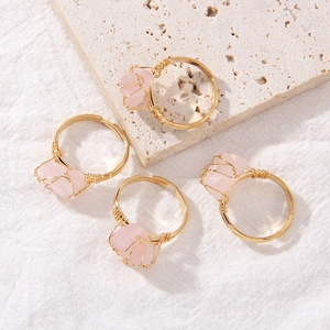Detail of four handmade gold wire wrapped rings with natural irregular pink quartz stones