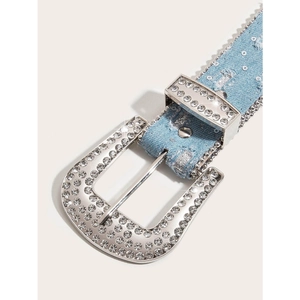 Detail of blue denim belt featuring shimmering rhinestones and a large silver metal buckle