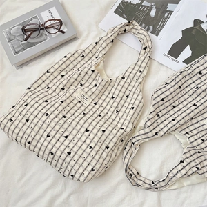 Close-up of heart print canvas tote bag with woven texture and vintage accessories