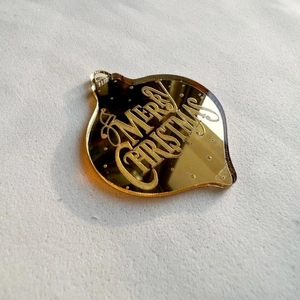 Macro shot of gold mirror acrylic waterdrop ornament with Merry Christmas engraving