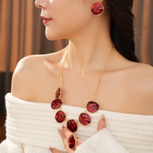 Detail of elegant gold-toned necklace and earrings set with deep red enamel texture