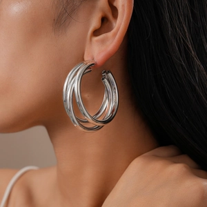 Close-up of triple-layered silver hoop earrings with high-polish metallic finish