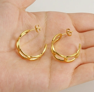 Detailed view of 18K gold plated interlocking twist hoop earrings held in hand