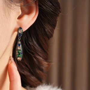 Vue latérale de boucles d'oreilles vintage en forme de goutte avec zircons multicolores