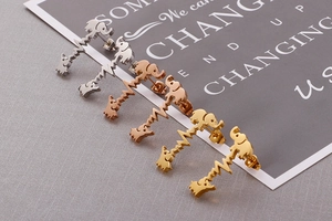 Detailed macro view of elephant and heartbeat stud earrings in gold, silver, and rose gold