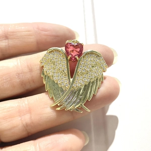 Detailed view of a gold angel wing pendant featuring a pink heart stone and zircon accents