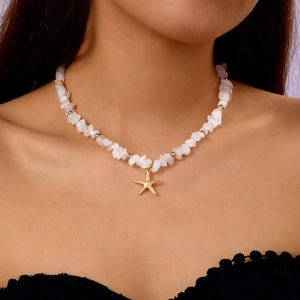 Detailed close-up of Bohemian gemstone necklace with golden starfish charm on model