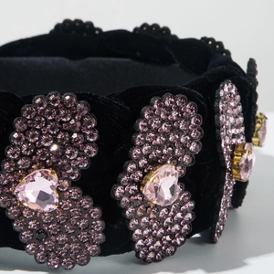 Dettaglio di un cerchietto in velluto nero con strass viola e cuori di cristallo rosa