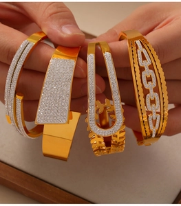 Gros plan de quatre bracelets dorés géométriques ajourés avec des zircons scintillants