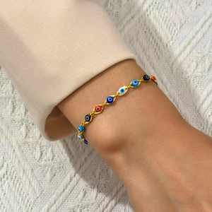 Gold Evil Eye bracelet with multi-colored charms worn on wrist with elegant apparel