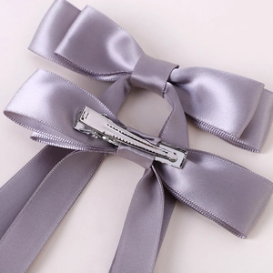 Pair of purple satin double-layer bow hair clips with elegant streamers on plain background