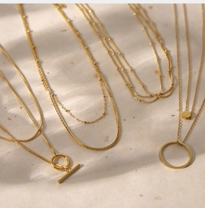 Close-up of 18K gold plated multi-layer necklaces with T-bar and ring pendants