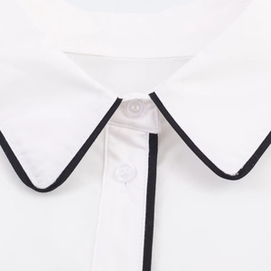 Detail of white poplin shirt collar featuring black contrast trim and transparent buttons