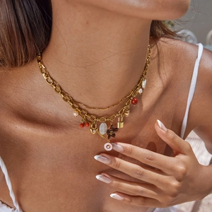 Close-up of multilayer gold stainless steel necklace with cherry, lock and pearl charms