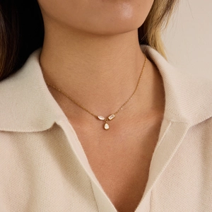Detail of 18K gold plated necklace with teardrop and geometric zircon pendants on model