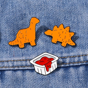 Spille in smalto dinosauro nugget arancione e ketchup su tessuto denim blu
