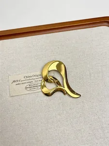 Detailed view of a gold-plated fluid abstract heart brooch on a beige linen display tray
