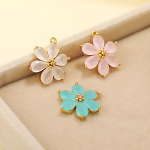 Detail of 18K gold plated six-petal flower pendants in white, pink and blue colors
