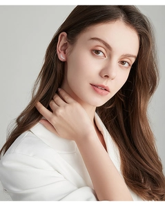 Detail showing high-quality curved moissanite earrings in 925 silver on a model ear