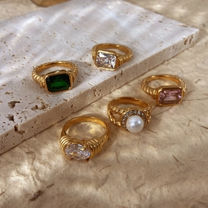 Detail von Vintage 18K vergoldeten Ringen mit Smaragd und Perle auf strukturiertem Stein