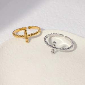 Detailed view of gold and silver beaded cross rings displayed on a ceramic tray