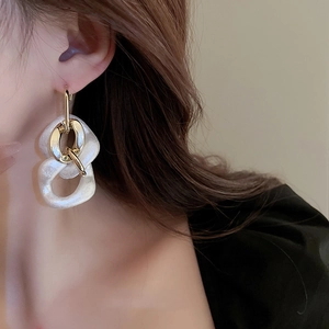 Chic gold earrings with white pearlescent acrylic chain pendants worn by a model