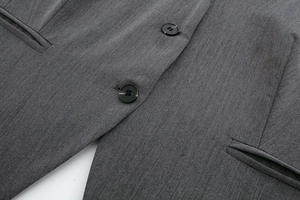 Détails d'un blazer gris montrant la texture du sergé, les boutons et les coutures