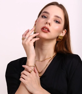 Model wearing gold 18K plated geometric earring, necklace and ring set on white background