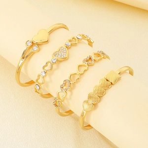 Detailed view of four-piece gold heart bangle set with sparkling white zircons on display