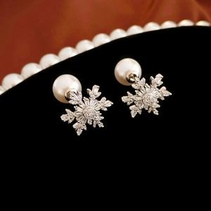 Elegant silver snowflake stud earrings with pearl and zircon on black velvet background