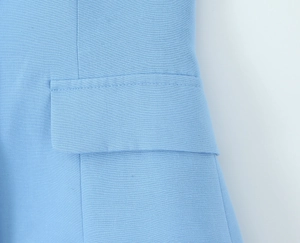 Detailed close-up of light blue blazer pocket with precise stitching and fabric texture
