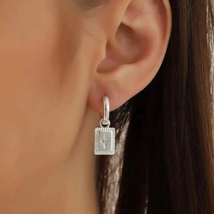 Silver drop earrings featuring an eight-pointed star and zircon pendant on a model