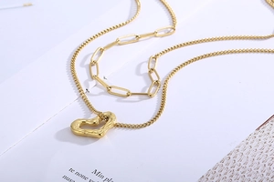Detail shot of golden double-layer chain necklace with irregular hollow heart pendant