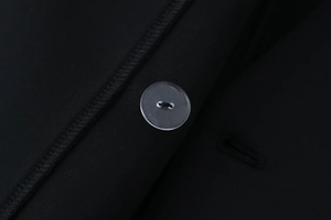 Macro detail of high-quality black suit fabric featuring a clear round button and stitching