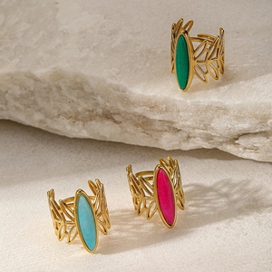 Detail of three vintage gold rings with green, blue, and pink stones on a natural rock
