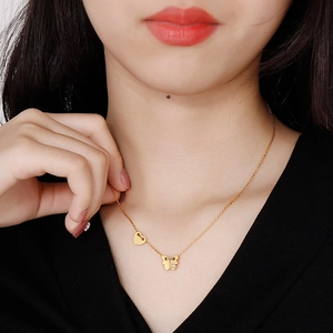 Elegant gold butterfly and heart pendant necklace with single diamond on model