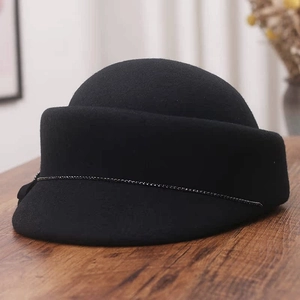 Close-up of black wool fedora with sparkling rhinestone chain detail on vintage wood