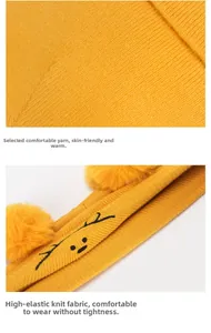 Gros plan détaillé du bonnet tricoté jaune moutarde pour bébé avec broderie et deux pompons