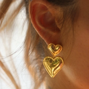 Close-up of double heart shaped 18k gold plated drop earrings worn by a model