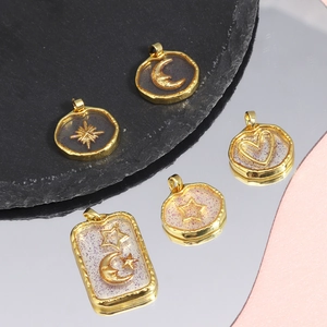 Detail of star and moon pendants in gold plating with black and white resin inlay