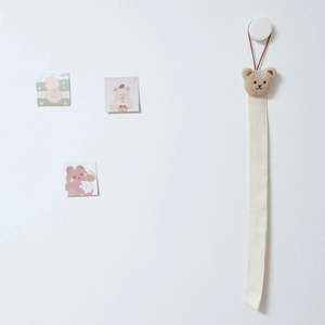 Brown plush bear wall hanging organizer with a long off-white canvas ribbon for hair clips