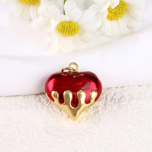 Macro detail of red dripping oil heart pendant with gold plated metal base