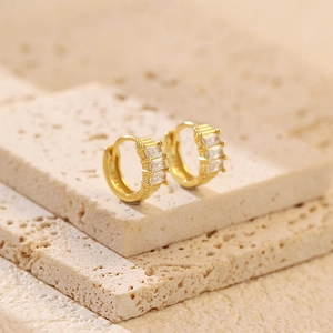 Macro shot of gold S925 silver huggie hoop earrings with rectangular zircon stones